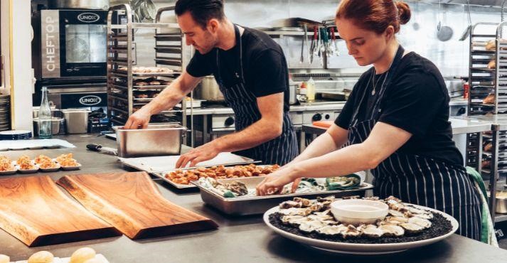 man-and-woman-in-black-apron-working-in-a-catering-kitchen